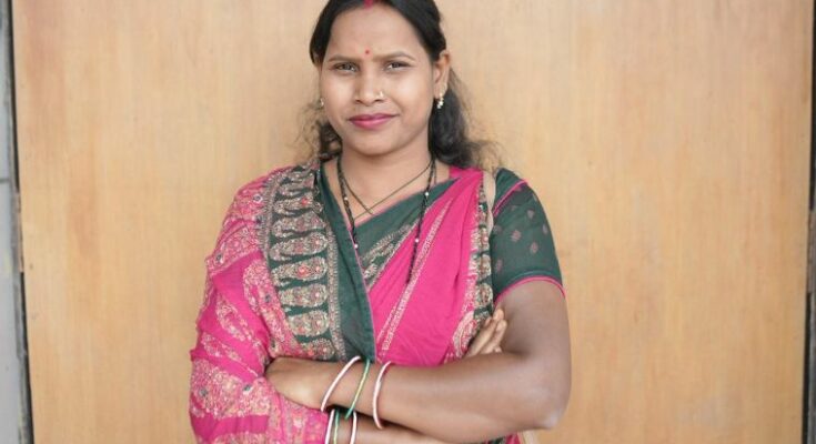 A confident rural Indian woman smiling while working at her own small shop, representing financial independence achieved through the Mahtari Vandan Yojana in Chhattisgarh.