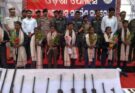 Surrendered Maoists laying down their arms before the Odisha Police and CRPF officials, signifying a major success in anti-Naxal operations.