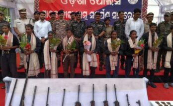 Surrendered Maoists laying down their arms before the Odisha Police and CRPF officials, signifying a major success in anti-Naxal operations.