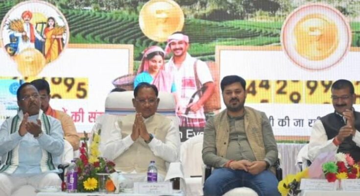 A happy Indian farmer in a green agricultural field holding a smartphone, representing the successful transfer of the PM Kisan 22nd installment in Chhattisgarh.