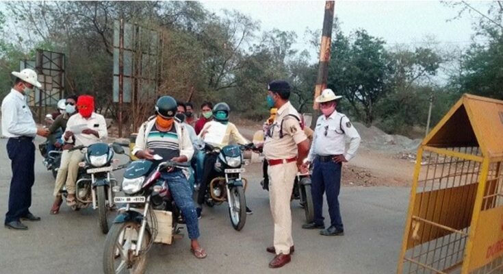 Traffic police personnel issuing an e-challan to a vehicle owner for using a fancy and defective number plate during a strict road safety drive.
