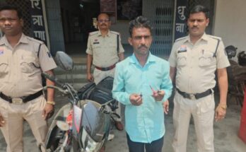 एक शातिर चोर का प्रतीकात्मक चित्र जो पेचकस से कार का शीशा तोड़ने की कोशिश कर रहा है और बैकग्राउंड में पुलिस की गाड़ी